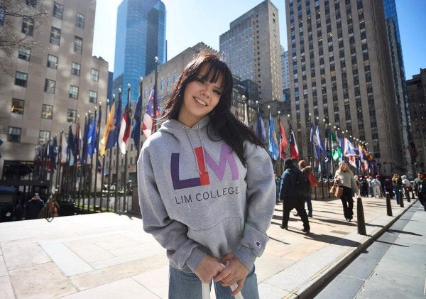 dark-haired young woman in LIM College hoodie, standing outdoors in Rockefeller Plaza