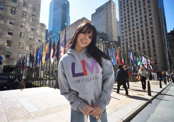 dark-haired young woman in LIM College hoodie, standing outdoors in Rockefeller Plaza