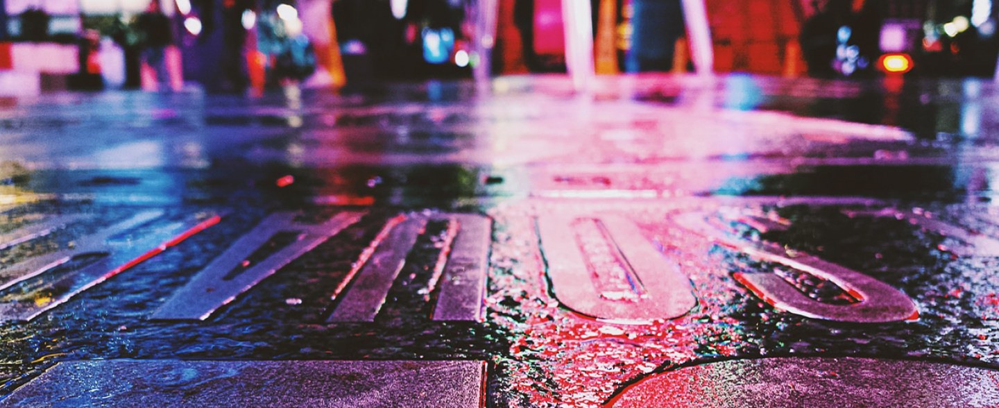 City lights shining against a wet pavement road.