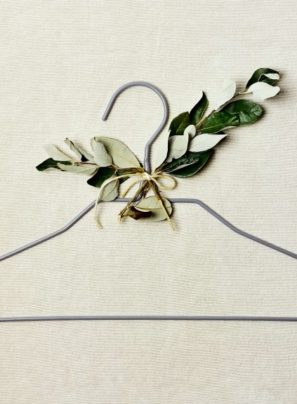 thin gray clothing hanger with leaves attached to it on beige background