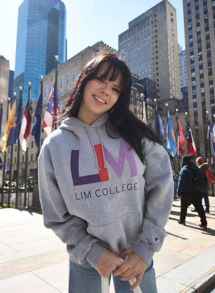 dark-haired young woman in LIM College hoodie, standing outdoors in Rockefeller Plaza