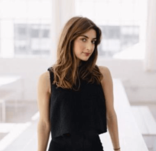 woman in black leaning against white tables 