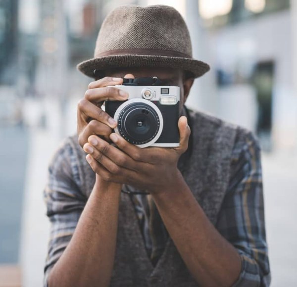 A man holds a point-and-shoot camera and is about to take a photograph