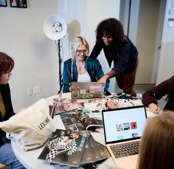 Five students gather around a table to discuss the latest issue of The Lexington Line student magazine