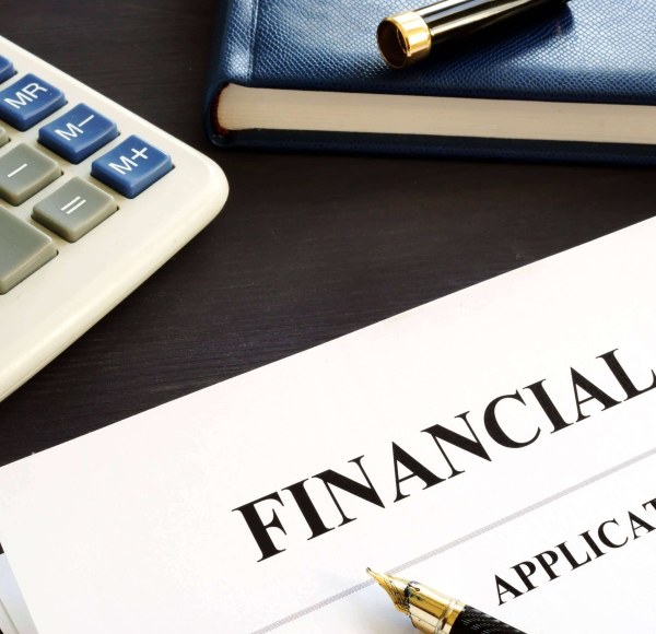 A financial aid application sits on a desk with a pen, calculator, and notebook nearby