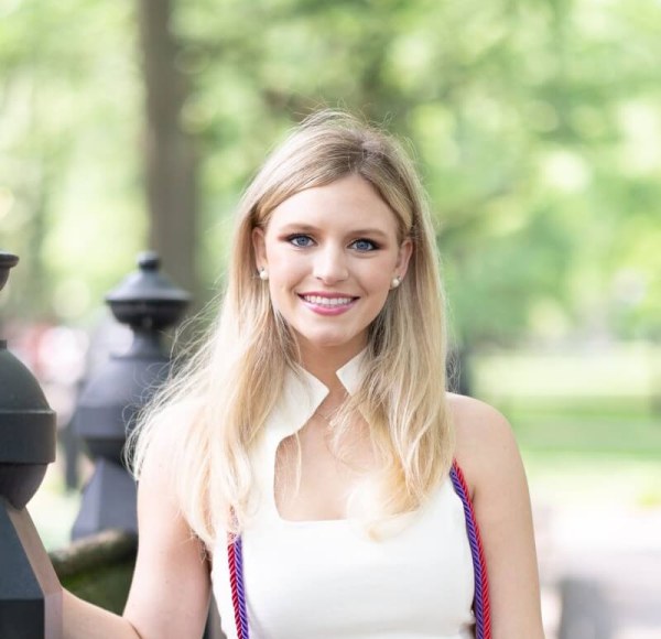 Mackenzie Schwers smiles and poses with trees in the background