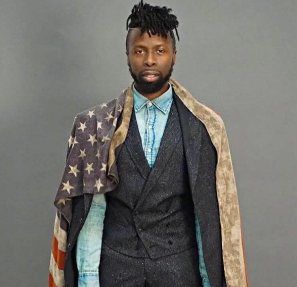 man with a flag draped over him looking at the camera