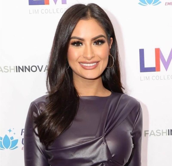 woman smiling at the camera in front of a step and repeat