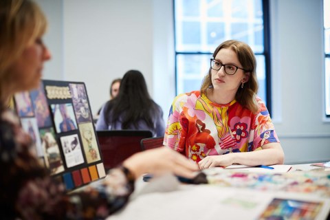 woman with glasses and floral shirt looking at a poster board