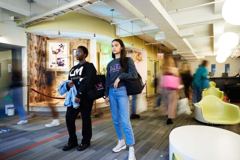 two female students in LIM sweathshirts standing in a lounge