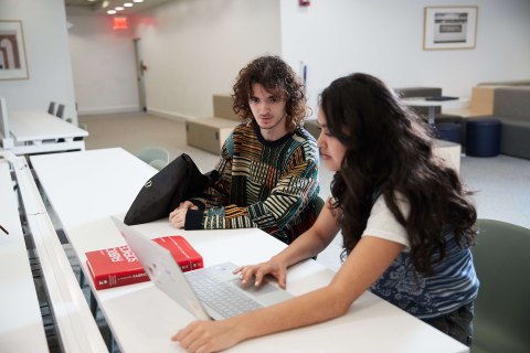 two students working together on a laptop