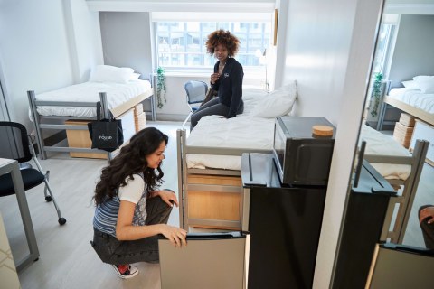 students sitting on bed and opening fridge