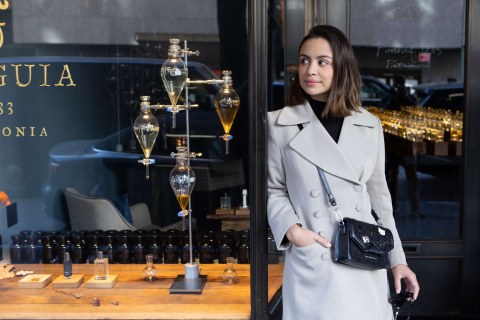 Young woman, gray overcoat standing in perfume store doorway