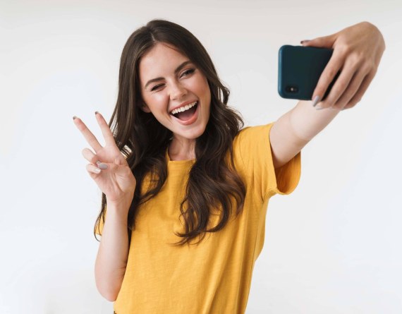 A woman makes a peace sign while taking a selfie